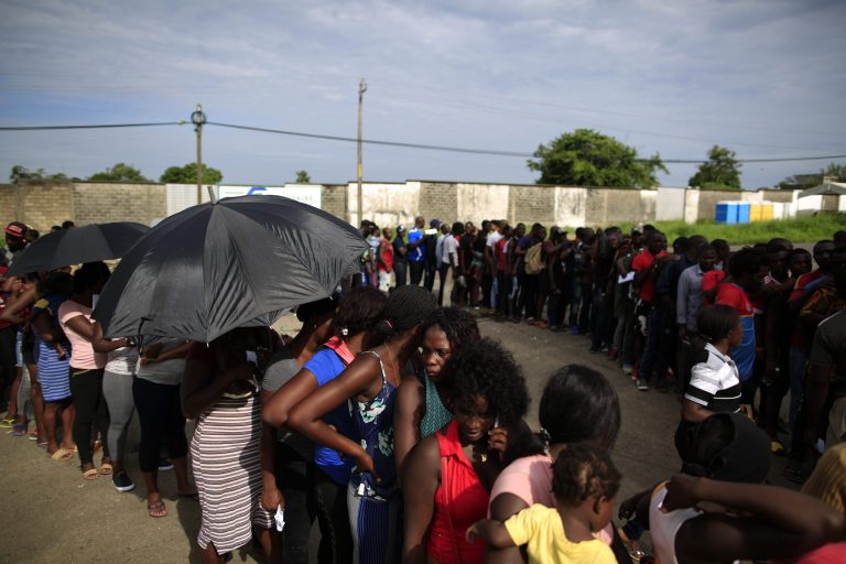 Mainly Haitian along with some African migrants wait in men's and women's lines.