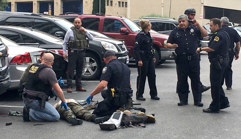 Law enforcement officers attend to an injured shooter in a parking lot after he fired shots at the Earle Cabell Federal Building in downtown Dallas.