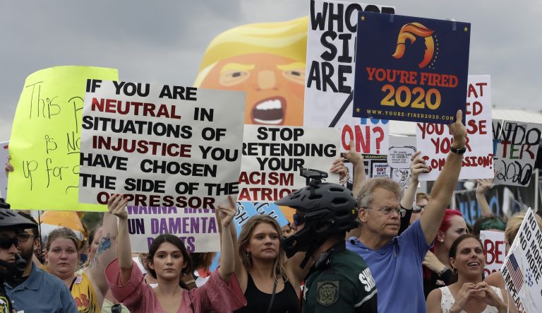 Protestors hold up anti President Donald Trump signs during a rally Tuesday, June 18, 2019, in Orlando, Fla. 