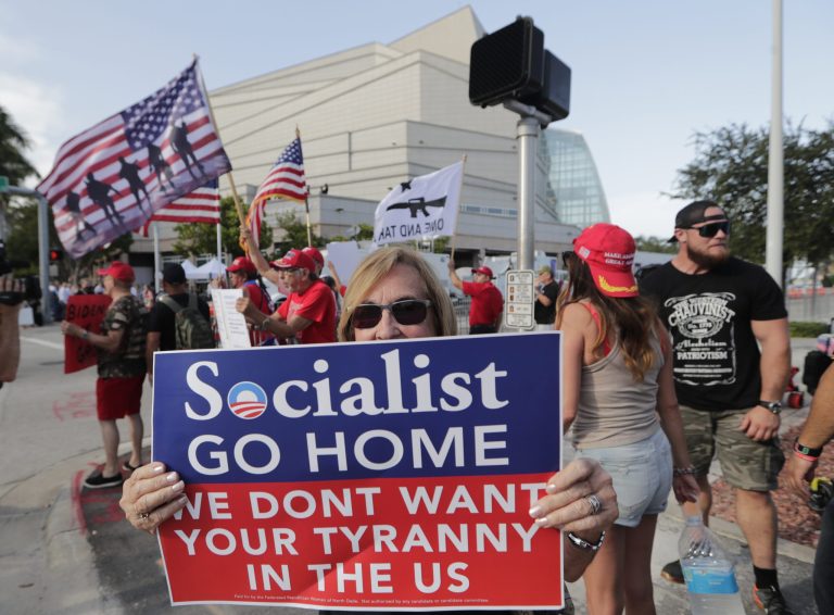 Teresa Gamez, a supporter of President Donald Trump, protests outside of the Knight Concert Hall at the Adrienne Arsht Center for the Performing Arts of Miami-Dade County, where the Democratic Presidential Debates are taking place, Wednesday, June 26, 2019, in Miami. (AP Photo/Lynne Sladky)