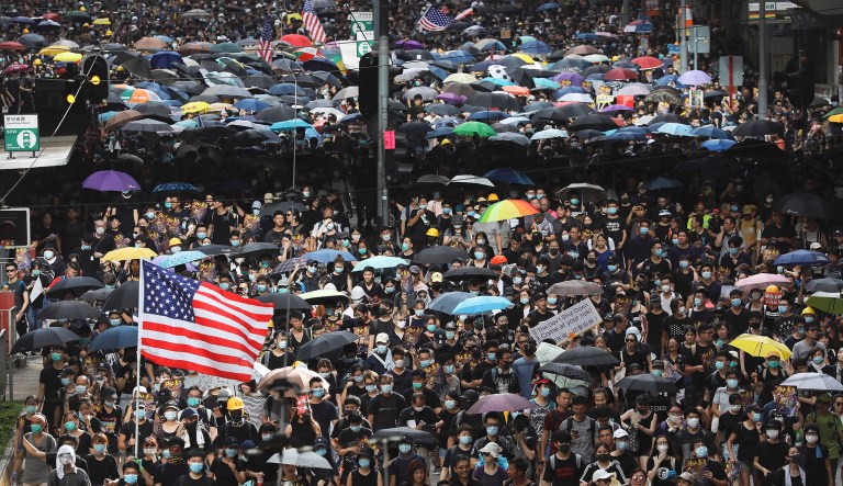 Protesters carry placards, U.S. flags, and umbrellas during a protest march in Hong Kong.