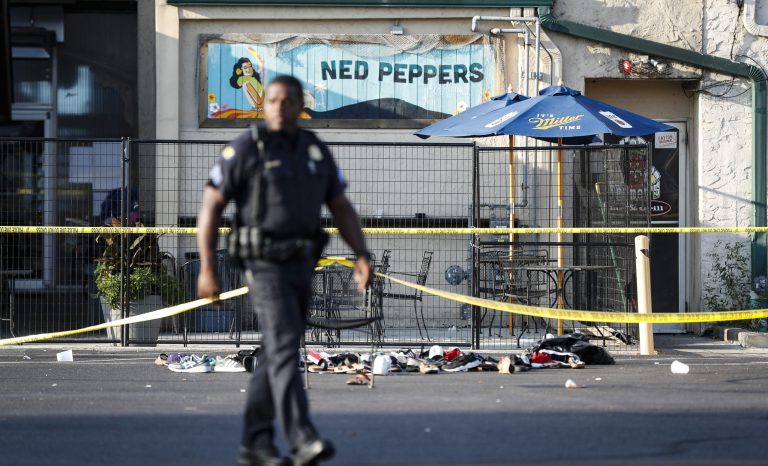 Shoes are piled outside the scene of a mass shooting including Ned Peppers bar, Sunday, Aug. 4, 2019, in Dayton, Ohio.