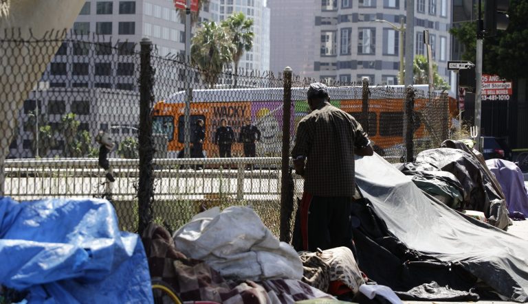 A newly displaced homeless camp is seen while Los Angeles Police officers guard a Harbor Freeway ramp in Los Angeles, Tuesday, Sept. 17, 2019. 