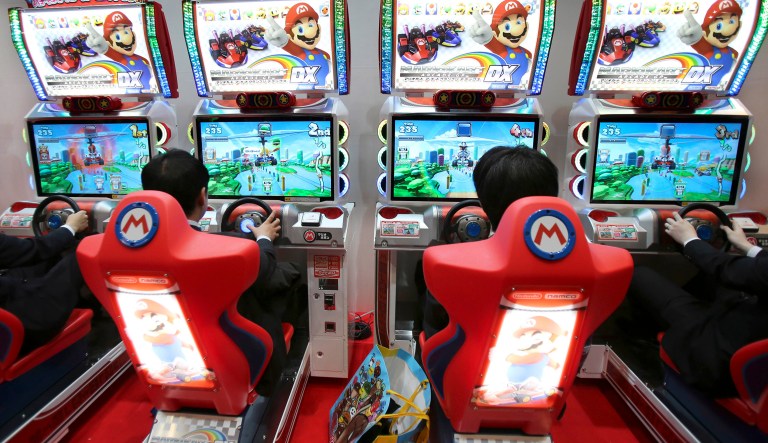 Visitors try out the Mario Kart Arcade GP DX racing game exhibited by Namco Bandai and Nintendo.