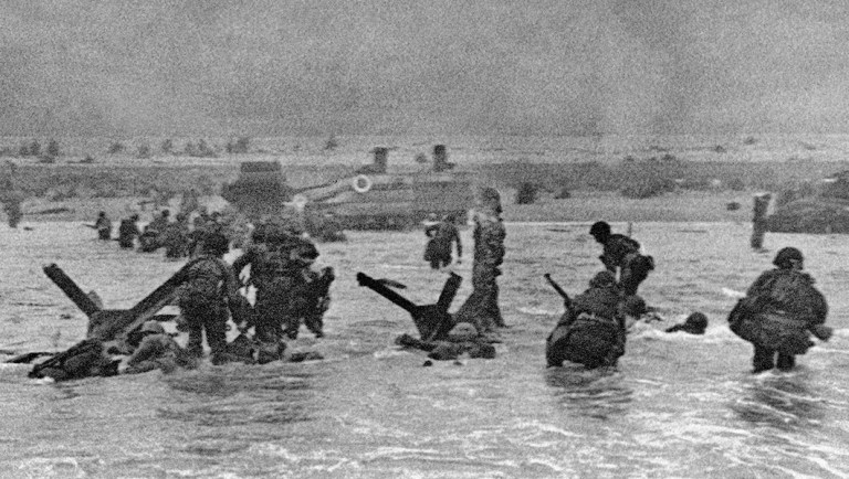 FILE - In this June 6, 1944 file picture, some of the first assault troops to hit the Normandy, France, beachhead take cover behind enemy obstacles.