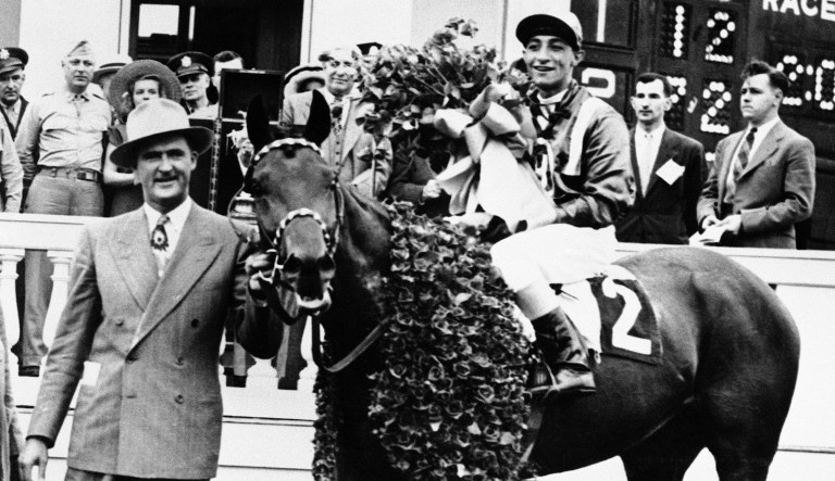 F.W. Hooper, of Jacksonville, Fla., smiles as he holds Hoop Jr., Kentucky Derby winner at Churchill Downs, Louisville, June 9, 1945. Jockey Eddie Arcaro is in the saddle.