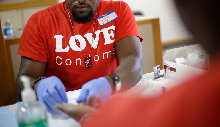 Reggie Batiste, left, program manager with AIDS Healthcare Foundation, administers a free HIV test as part of National HIV Testing Day, Thursday, June 27, 2013, in Atlanta.