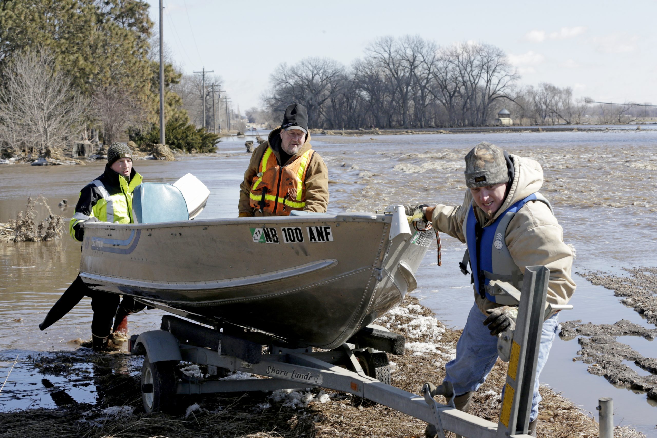 Tom Wilke, center, his son Chad, right, and Nick Kenny, load a boat out of the swollen waters of the North Fork of the Elkhorn River after checking on the Wilke's flooded property, in Norfolk, Neb., on Friday.