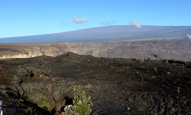In this April 25, 2019 photo, Hawaii's Mauna Loa volcano, background, towers over the summit crater of Kilauea volcano in Hawaii Volcanoes National Park on the Big Island.