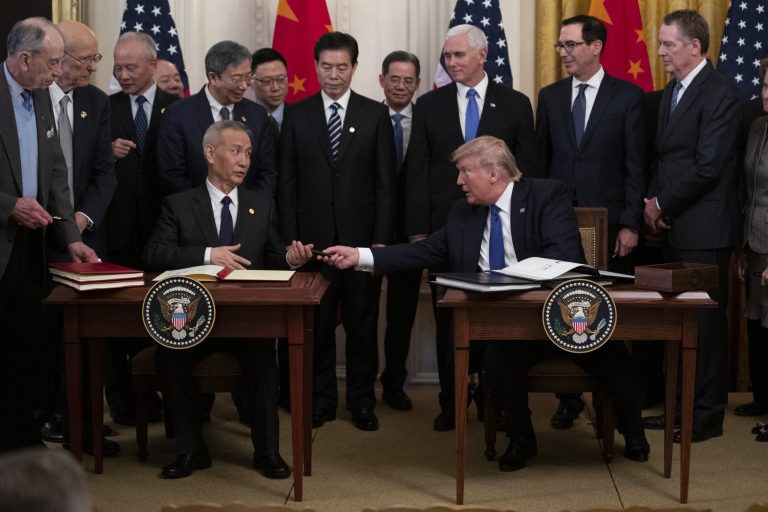 In this Jan. 15, 2020, photo, President Donald Trump hands a pen to Chinese Vice Premier Liu He after signing "phase one" of a US China trade agreement, in the East Room of the White House in Washington.