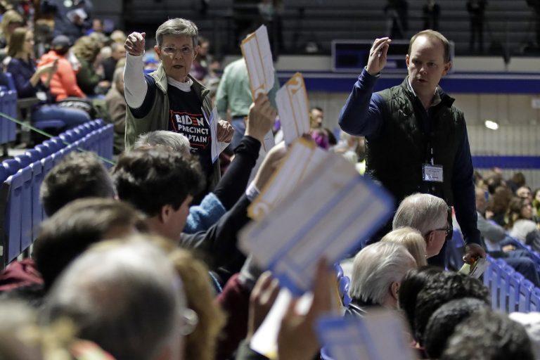 Caucus goers seated in the section for Democratic presidential candidate former Vice President Joe Biden hold up their first votes as they are counted at the Knapp Center on the Drake University campus in Des Moines, Iowa, Monday, Feb. 3, 2020.
