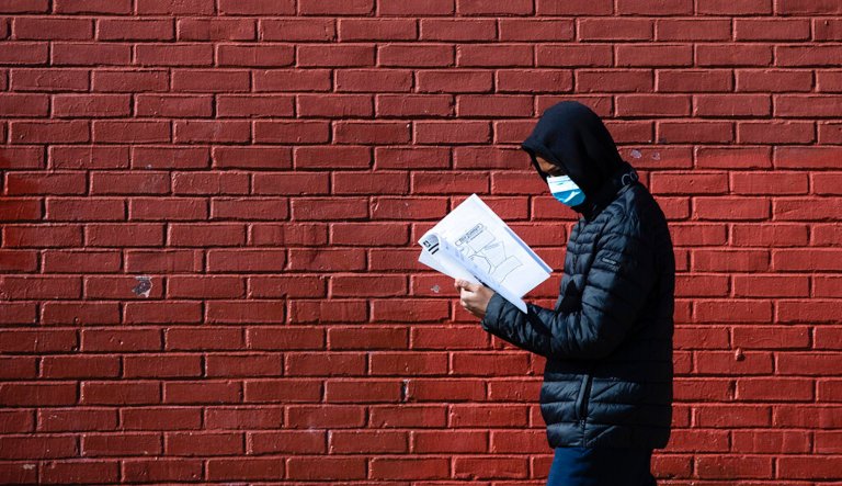 Terrell Bell, wearing a protective face mask, looks at a learning guide he picked up for his little sister at John H. Webster Elementary School in Philadelphia, Thursday, March 26, 2020. Gov. Tom Wolfâs administration reported more new coronavirus-related deaths in Pennsylvania on Wednesday. Residents are ordered to stay home, with few exceptions.