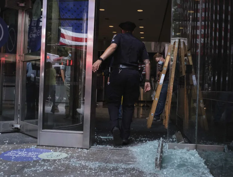 NYPD look over damage to a building near City Hall Park, Wednesday, July 15, 2020, in New York.  Several New York City police officers were attacked and injured Wednesday on the Brooklyn Bridge during a protest sparked by the death of George Floyd. Police say at least four officers were hurt, including the departmentâs chief, and more than a dozen people were arrested.
