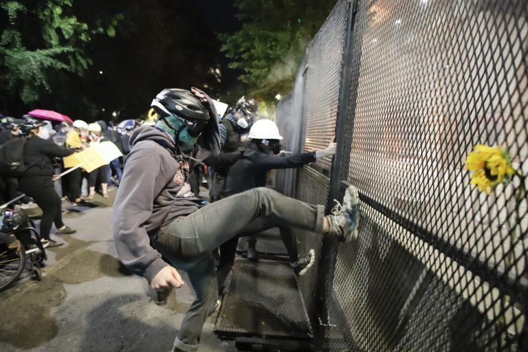 Demonstrators tried to kick down a fence during a Black Lives Matter protest at the Mark O. Hatfield United States Courthouse Thursday, July 23, 2020, in Portland, Ore. Polls showing support for a crackdown.