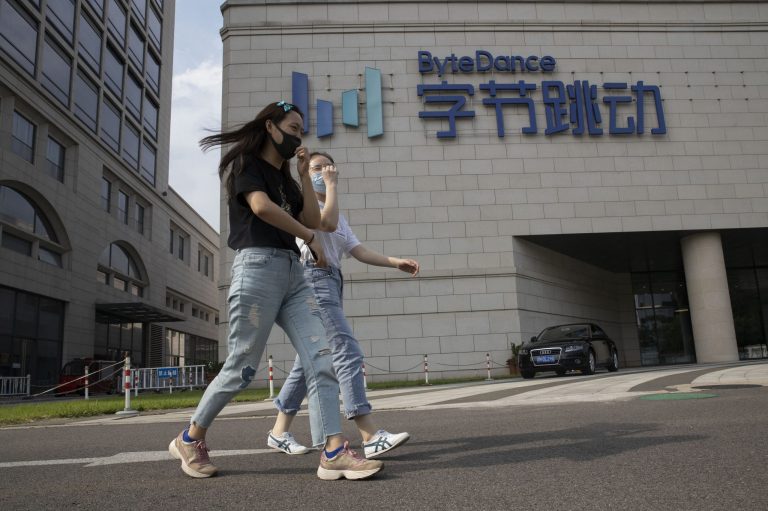 Women wearing masks to prevent the spread of the coronavirus chat as they pass by the ByteDance headquarters in Beijing, China on Friday, Aug. 7, 2020.