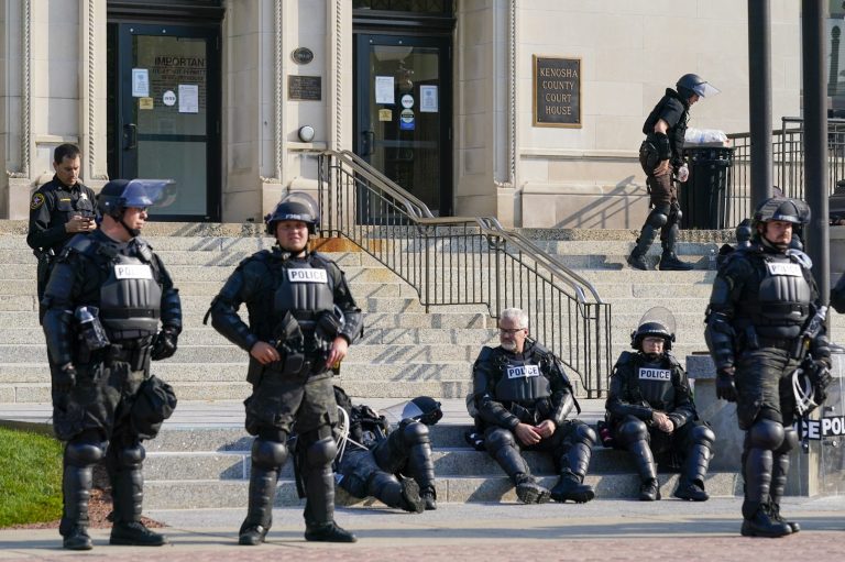 Police in riot gear stand outside the Kenosha County Court House Monday, Aug. 24, 2020, in Kenosha, Wis. Kenosha police shot a man Sunday evening, setting off unrest in the city after a video appeared to show the officer firing several shots at close range into the man's back. (AP Photo/Morry Gash)