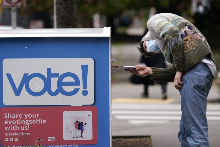 A voter turns sideways as he eyes the opening of a ballot drop box before placing his ballot inside it Wednesday, Oct. 28, 2020, in Seattle. Washington state is one of five states, along with Colorado, Hawaii, Oregon, and Utah, that conduct elections entirely by mail-in voting. 