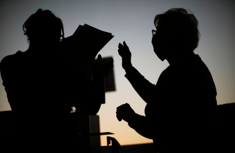 Election inspectors gather around a machine as it counts ballots on Election Day at City Hall in Warren, Mich., in Macomb County, Tuesday, Nov. 3, 2020. 