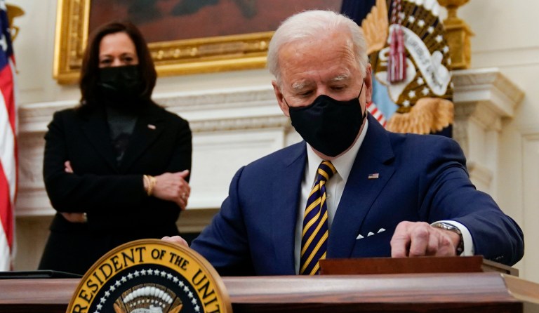 President Joe Biden signs executive orders on the economy in the State Dining Room of the White House, Friday, Jan. 22, 2021, in Washington. Vice President Kamala Harris looks on at left.