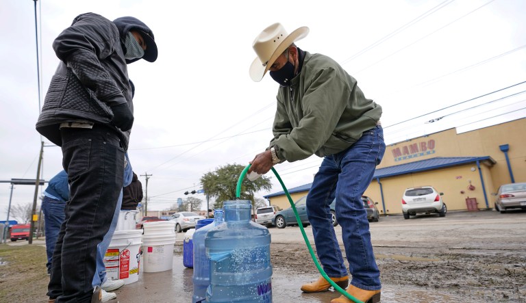 Leovardo Perez, right, fills a water jug using a hose from a public park water spigot Thursday, Feb. 18, 2021, in Houston. Houston and several surrounding cities are under a boil water notice as many residents are still without running water in their homes.