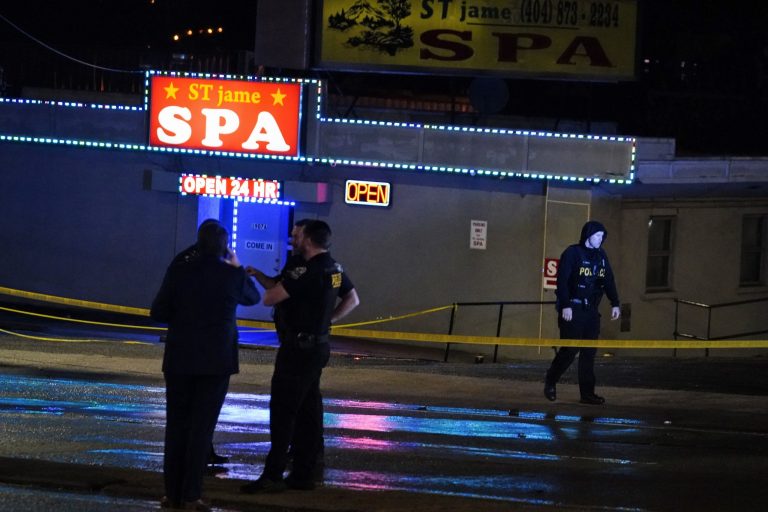Law enforcement officials confer outside a massage parlor following a shooting on Tuesday, March 16, 2021, in Atlanta. (AP Photo/Brynn Anderson)