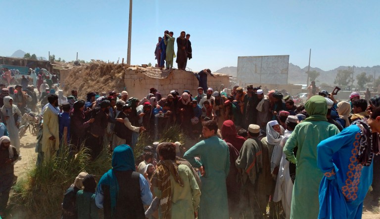 Taliban fighters and Afghan people gather around the dead body of security personnel inside the city of Farah, capital of Farah province southwest of Kabul, Afghanistan, Wednesday, Aug. 11, 2021.