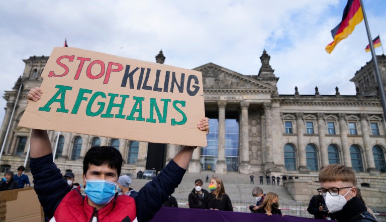 A man holds a poster during a demonstration in Berlin, Germany, Tuesday, Aug. 17, 2021. Several hundreds of people attend a demonstration to support an air bridge to bring people out of the Taliban controlled country.