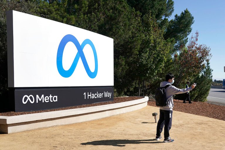 A Facebook employee take a selfie in front the company's new name and logo outside its headquarters in Menlo Park, California.