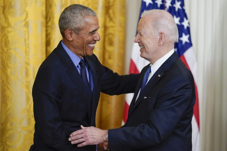 Former President Barack Obama shakes hands with President Joe Biden after Biden spoke about the Affordable Care Act in the East Room.