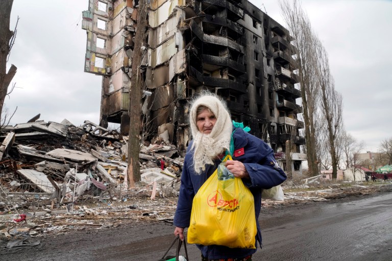 An elderly woman walks by an apartment building destroyed in the Russian shelling of Borodyanka, Ukraine.