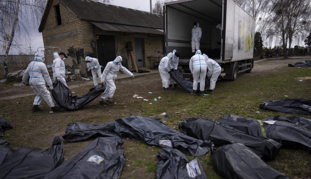 Volunteers load bodies of civilians killed in Bucha onto a truck to be taken to a morgue for investigation, in the outskirts of Kyiv, Ukraine, Tuesday, April 12, 2022.