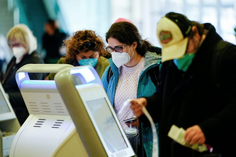 Travelers wearing protective masks as a precaution against the spread of the coronavirus check in at the Philadelphia International Airport in Philadelphia, Tuesday, April 19, 2022.  