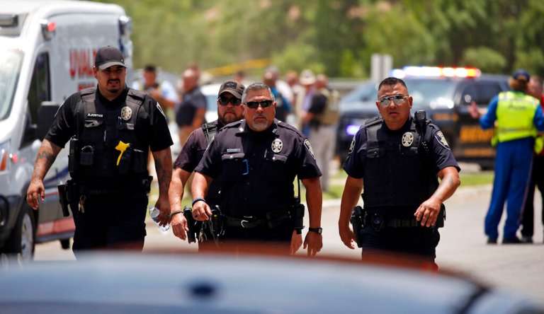 Police walk near Robb Elementary School following a shooting, Tuesday, May 24, 2022, in Uvalde, Texas.