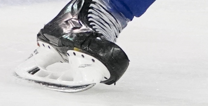 A hockey skate cuts through the ice.