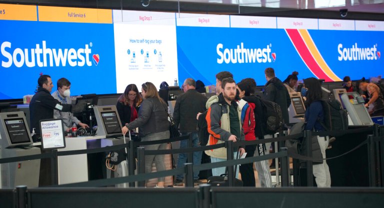 FILE - Travelers queue up at the check-in counters for Southwest Airlines in Denver International Airport, Friday, Dec. 30, 2022, in Denver. Southwest Airlines is trying to fix its relationship with travelers who got stuck by canceled flights over the holidays. On Tuesday, Jan. 3, 2023, Southwest told affected travelers that they will get 25,000 frequent-flyer points, which are worth more than $300 in tickets.