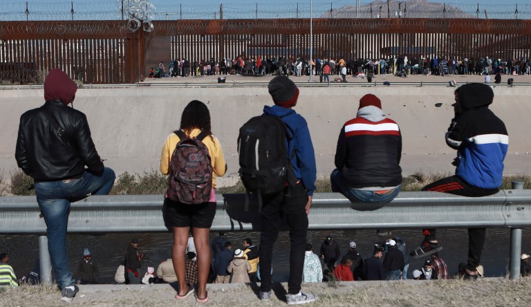 Migrants watch others stand next to the border wall in Ciudad Juarez, Mexico, Dec. 21, 2022, on the other side of the border from El Paso, Texas.