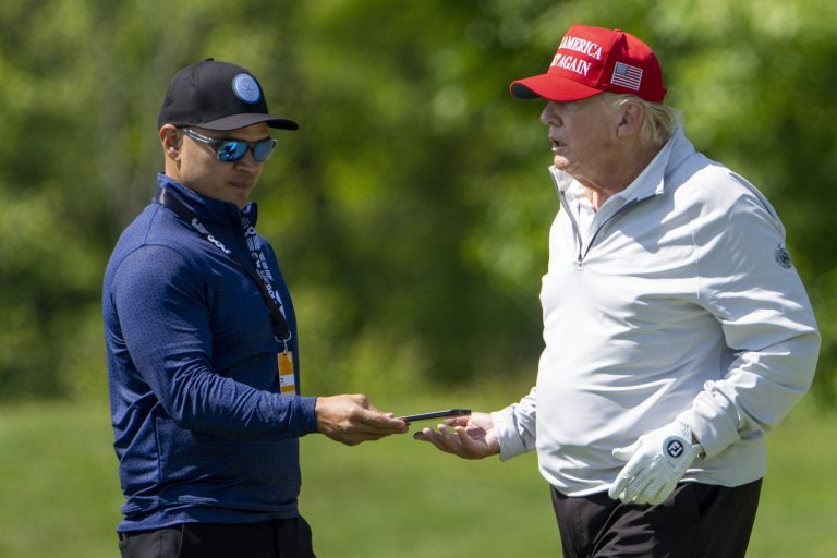 Walt Nauta, left, takes a phone from former President Donald Trump during the LIV Golf Pro-Am at Trump National Golf Club, May 25, 2023, in Sterling, Virginia. 