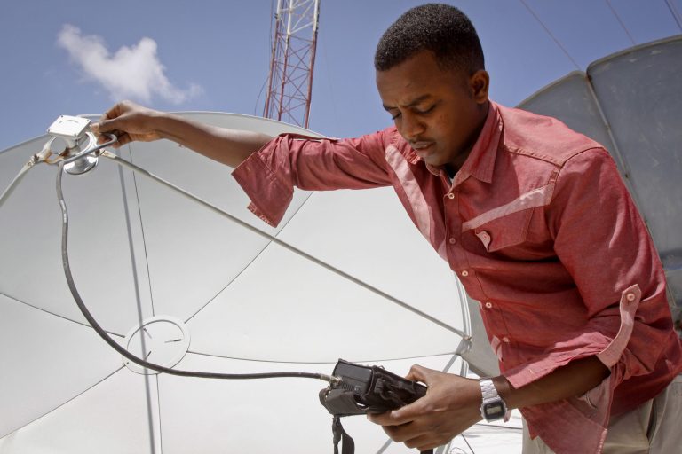 In this photo taken Monday, Aug. 4, 2014, a technician from Access TV, a new Somali satellite television company offering world news, local news and sports, adjusts the signal on a satellite dish at the company's headquarters in Mogadishu, Somalia.  The TV business is booming in Somalia, in part because of fears by people of gathering in public places like movie theaters, hotels and restaurants that are targeted for deadly attacks by the al-Qaida-linked militant group al-Shabab. (AP Photo/Farah Abdi Warsameh)