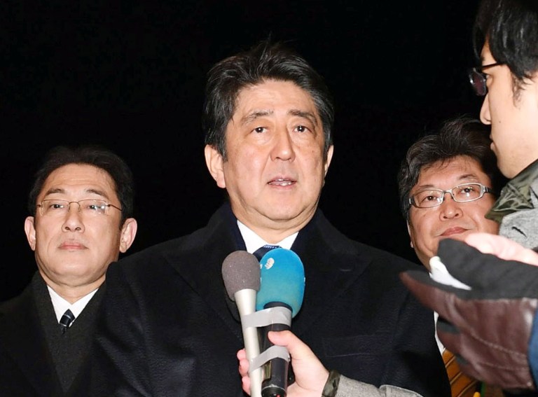 Japanese Prime Minister Shinzo Abe, center, speaks to reporters before leaving for the United States at Haneda international airport in Tokyo Thursday, Feb. 9, 2017. Abe left Japan for Washington to meet U.S. President Donald Trump on Friday. At left is Japanese Foreign Minister Fumio Kishida. (Hitoshi Takano/Kyodo News via AP)