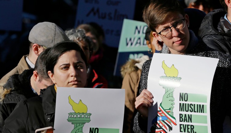 Protesters hold signs that read 