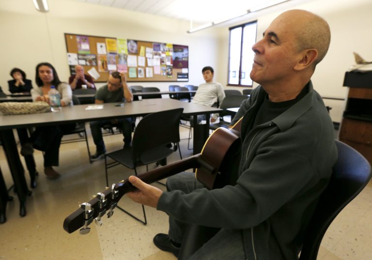   In this Oct. 10, 2012, photo, musician Julio Fernandez holds a guitar during a class session at Montclair State University in Montclair, N.J. Students are participating in a music class for service men and women that helps them cope with their life after the military through a program called Voices of Valor. (AP Photo/Julio Cortez)  
