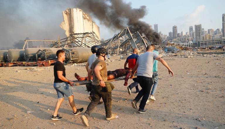 Civilians carry a person at the explosion scene that hit the seaport, in Beirut Lebanon, Tuesday, Aug. 4, 2020.