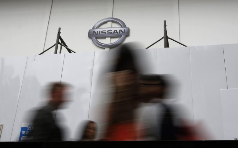 People walk past a wall set up in front of Nissan's showroom under renovation in Tokyo, Monday, May 12, 2014. Nissan's quarterly profit edged up nearly 5 percent as sales grew around the world and a favorable exchange rate helped earnings. Nissan Motor Co. reported Monday that January-March profit totaled 114.9 billion yen ($1.1 billion), up from 109.7 billion yen the year before. (AP Photo/Shizuo Kambayashi)
