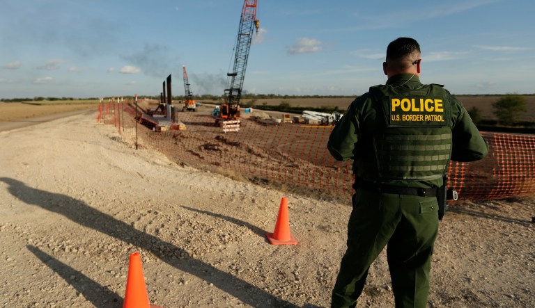 A U.S. Border Patrol agent stands over a construction site for a new section of levee border wall along the U.S.-Mexico border, Thursday, Nov. 7, 2019, in Donna, Texas. The new section, with 18-foot tall steel bollards atop a concrete wall, will stretch approximately 8 miles.
