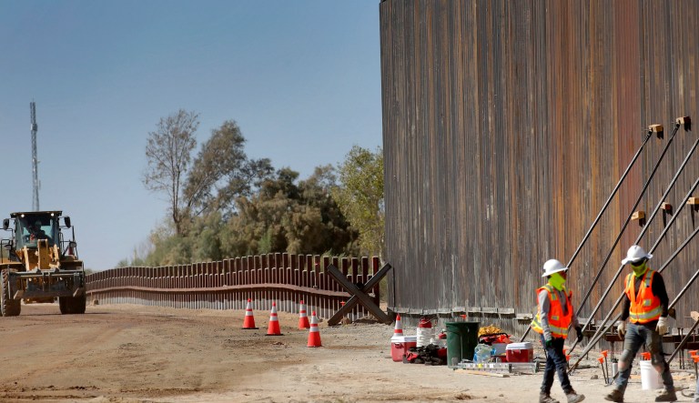 A man passes new border wall sections, right, as they replace the old fencing, left, Friday, Jan. 10, 2020, near Yuma, Arizona. Top Trump administration officials will visit South Texas five days before Election Day to announce they have completed 400 miles of U.S.-Mexico border wall, attempting to show progress on perhaps the president's best-known campaign promise four years ago. But most of the wall went up in areas that already had smaller barriers.