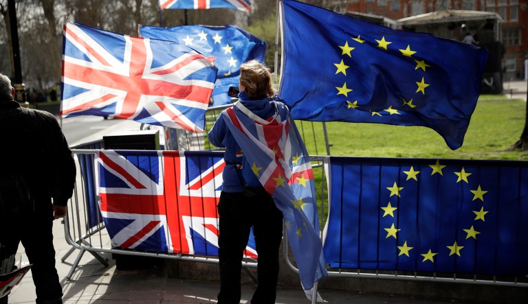 An anti-Brexit supporter stands by European and British Union flags placed opposite the Houses of Parliament in London, Monday, March 18, 2019.