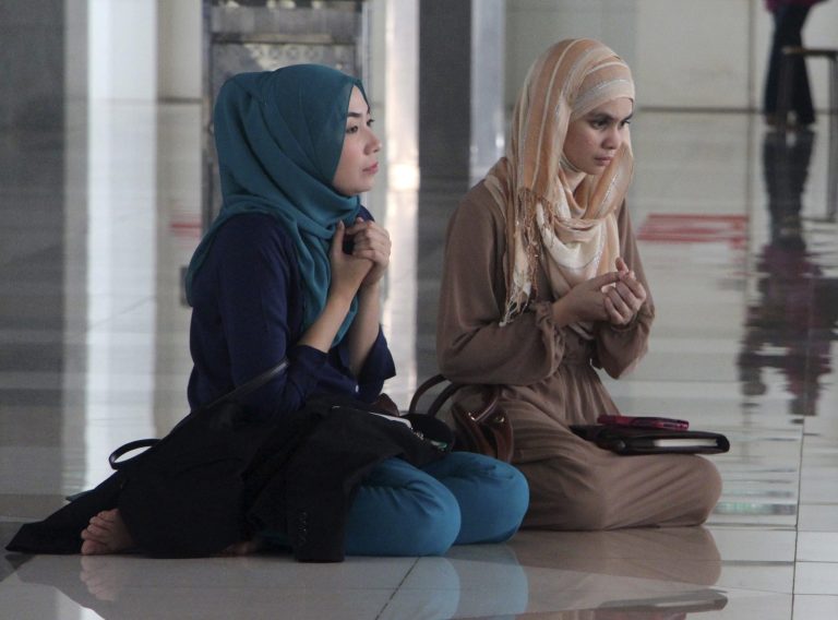 Two women pray with others during a prayer session organized by former schoolmates of a cabin crew member of Malaysia Airlines Flight 17, which was shot down in Ukraine, at a mosque in Kuala Lumpur, Malaysia Saturday, July 19, 2014. Malaysia's transport minister said the country is 