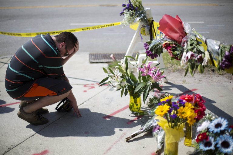 A resident of Charleston, S.C., kneels at a makeshift memorial down the street from where a white man opened fire Wednesday night during a prayer meeting inside the Emanuel AME Church killing several people in Charleston, Thursday, June 18, 2015. (AP Photo/David Goldman)