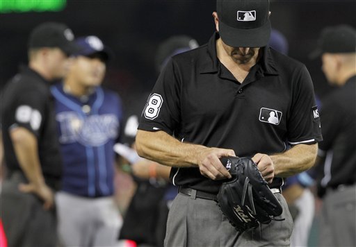 Umpire Chris Guccione leaves with the glove of Tampa Bay Rays relief pitcher Joel Peralta during the eighth inning of the Rays' baseball game against the Washington Nationals on Tuesday, June 19, 2012, in Washington. Peralta was ejected in the eighth inning for having a foreign substance on his glove. (AP Photo/Alex Brandon)