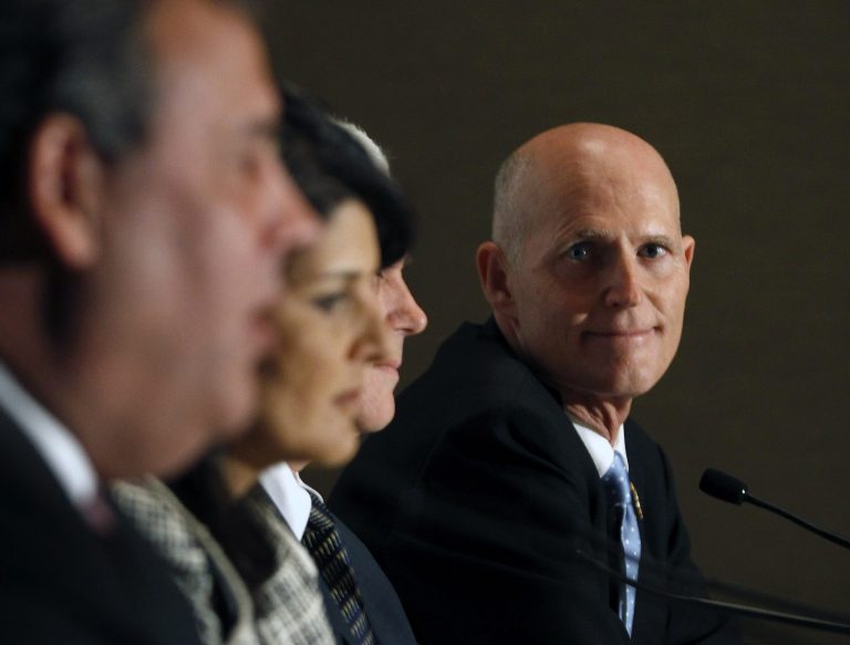 Florida Gov. Rick Scott, right, listens alongside several fellow Republican state executives as New Jersey Gov. Chris Christie, left, speaks during a press briefing for the Republican Governors Association 2013 annual conference at The Phoenician Resort on Thursday in Scottsdale, Ariz. (AP Photo/Ralph Freso)